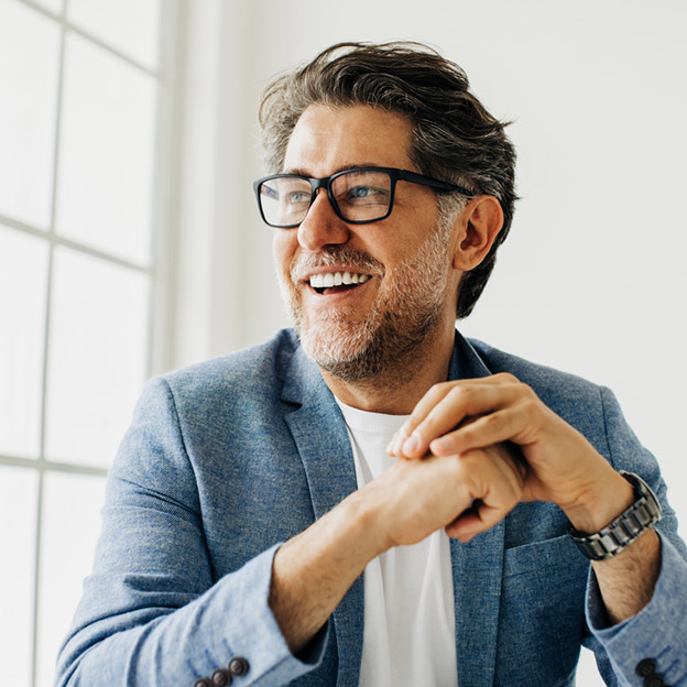 Hombre adulto sonriendo con dientes fijos tras una rehabilitación de boca completa